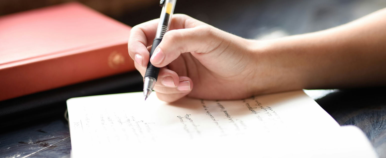 weibliche Hand mit Stift auf einem Notizblock