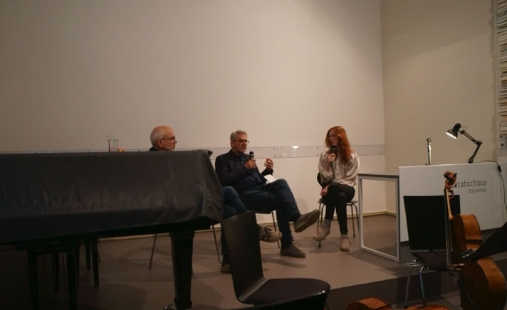 Die Autorin Nicola Quaß im Gespräch mit dem Schriftsteller Kurt Drawert auf der Bühne des Literaturhauses Darmstadt während der Lesebühne am 6. Mai 2026. Im Vordergrund sind ein abgedeckter Flügel sowie Violoncelli zu sehen.