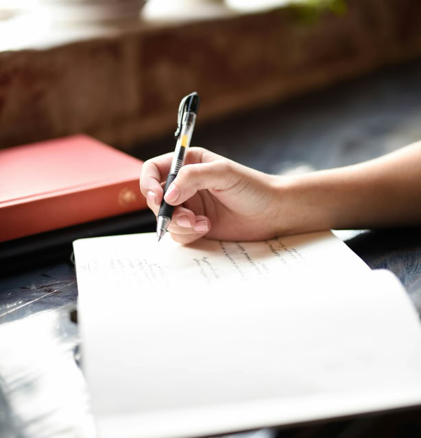 weibliche Hand mit Stift auf einem Notizblock