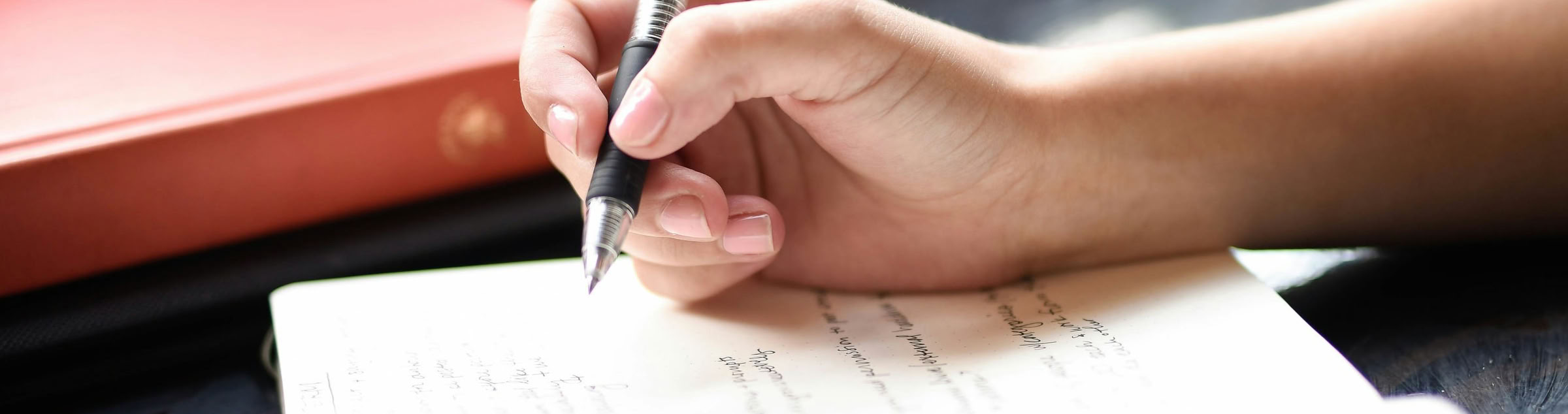 weibliche Hand mit Stift auf einem Notizblock