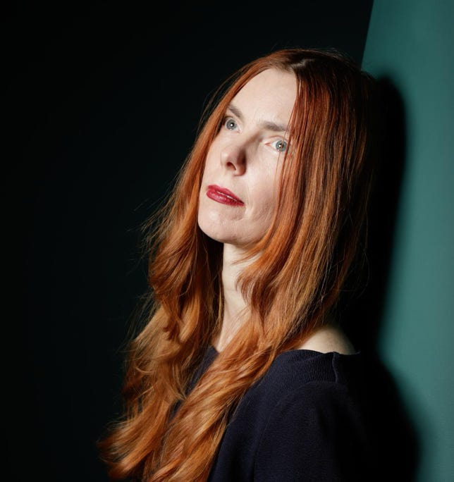 <img source='pic.gif' alt='Porträtbild der Düsseldorfer Autorin und Dichterin Nicola Quaß die Autorin hat lange rote Haare und lehnt sich gedankenversunken an eine grüne Wand'/>